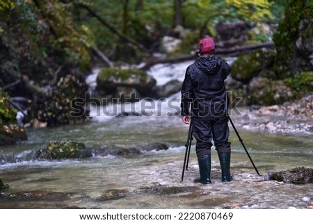 Professional nature photographer shooting landscapes in a canyon with a river in a rainy morning