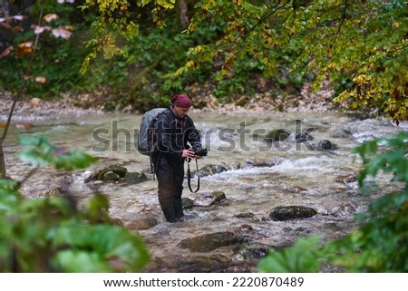 Professional nature photographer shooting landscapes in a canyon with a river in a rainy morning