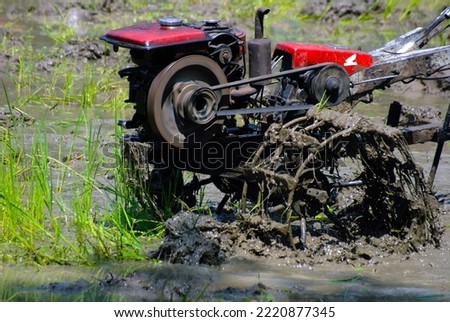 tractor in muddy farming land preparing paddy field