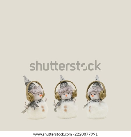 Three snowmen with headphones on pastel beige background. Creative composition for winter holidays, Christmas, New Year.