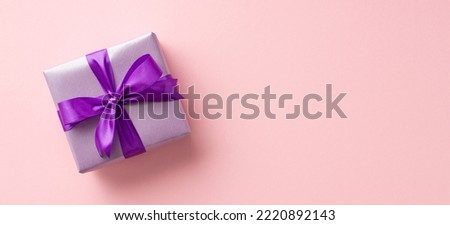 New Year concept. Top view photo of lilac present box with violet ribbon bow on isolated light pink background with copyspace