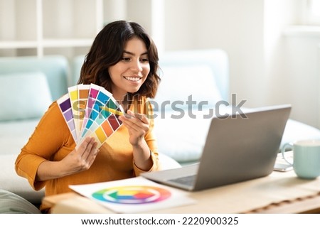 Young Arab Interior Designer Lady Showing Swatches To Client Via Teleconference On Laptop, Smiling Middle Eastern Woman Demonstrating Color Examples During Video Call On Computer, Free Space