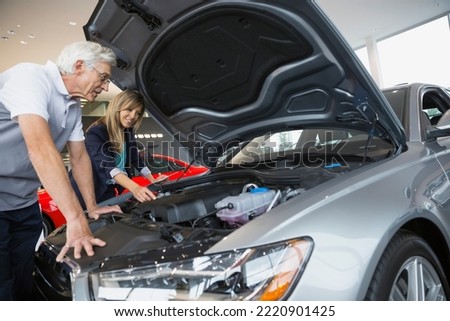 Saleswoman and man looking at engine in showroom