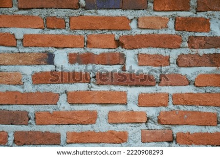 a patch of wall made of neat arrangement of red bricks