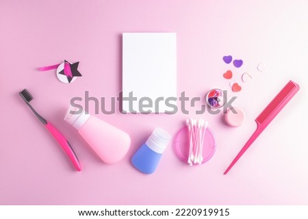 Girly flatlay with white notebook page and daily self care cosmetics arranged on pink background. Top view, copy space.