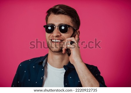 Portrait of a happy man using smartphone isolated over pink background.