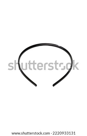 Subject shot of a thin black headband. The hairband is isolated on the white background with shadows. Vogue accessory for ladies and girls.