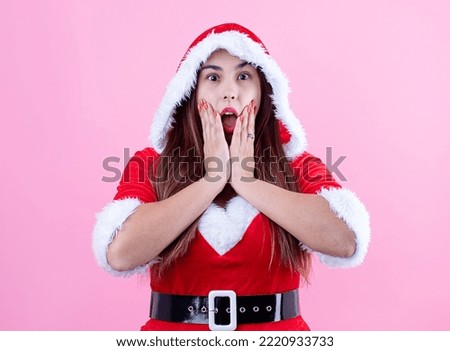 closeup of surprised caucasian woman wearing santa clothes on pink solid background