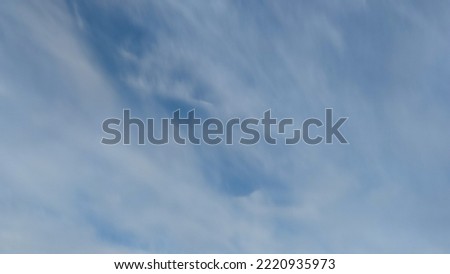 Pale blue sky with clouds. Autumn evening high in the sky are translucent white-gray cirrus clouds. They are blurry translucent through them you can see the pale blue sky.