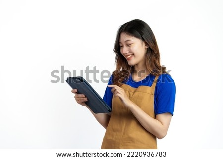 Using tablet, Cheerful young pretty asian woman blue t-shirt and apron coffee owner isolated on white background. checking order online