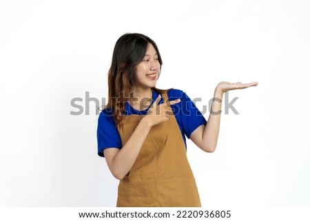 Palm up, Cheerful young pretty asian woman blue t-shirt and apron coffee owner isolated on white background.
