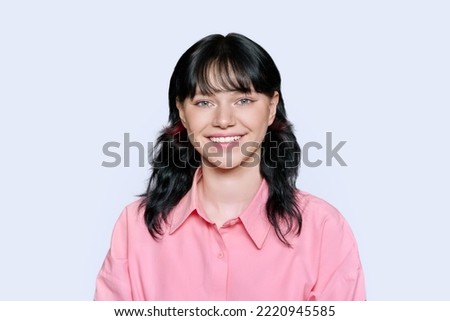 Smiling young female looking at camera on light background