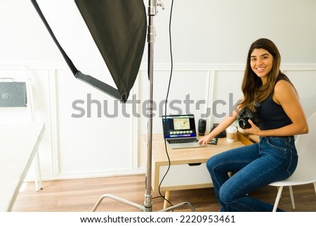 Portrait of a cheerful female photographer doing photo editing and checking the pictures after a professional shooting