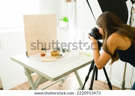 Professional female photographer doing a photo shooting at her studio with camera equipment an lighting