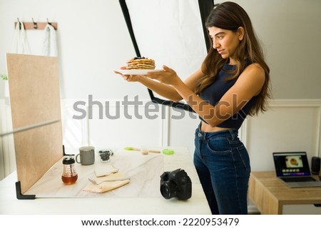 Attractive young woman working as a photographer and doing a professional shooting while food styling