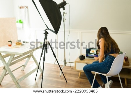 Young female photographer using the laptop to do photo editing after a studio shooting