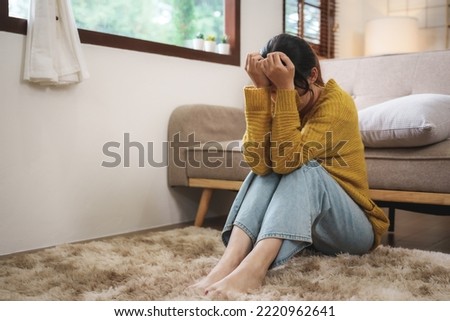 Young Asian woman suffering from work stress sits alone on the sofa at home discouraged. Desperate Asian woman feeling lonely