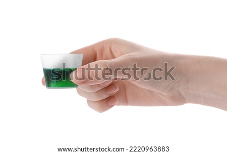 Woman holding measuring cup with syrup isolated on white, closeup. Cough and cold medicine Royalty-Free Stock Photo #2220963883