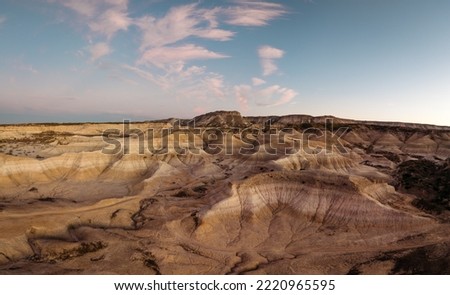 Arid desert landscape and striking geological formations in semi-desert landscape at sunset. Panoramic view. Valle de la Luna Amarillo, General Roca, Argentina Royalty-Free Stock Photo #2220965595