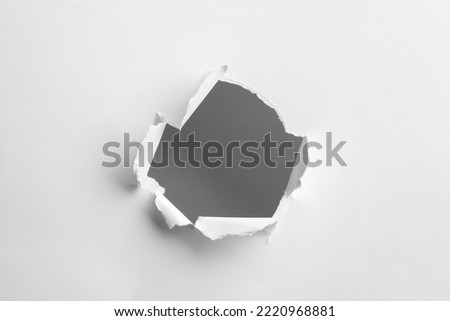 Hole in white paper on light background Royalty-Free Stock Photo #2220968881