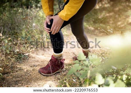 A woman is holding her knee joint in excruciating pain at uphill road. Royalty-Free Stock Photo #2220976553