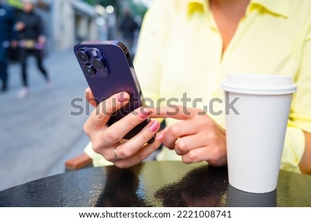 Woman using cell phone while sitting in outdoor street cafe