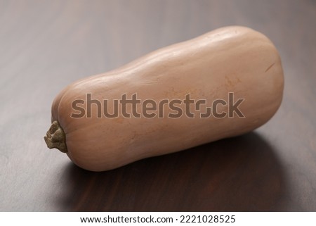 Whole butternut squah on walnut wood table Royalty-Free Stock Photo #2221028525