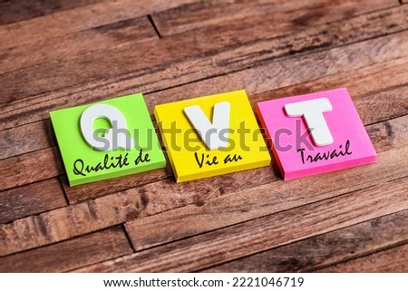 Square notepads colored wooden letters: french acronym QVT means Quality of life at work