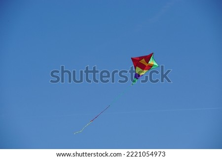 Beautiful colorful kite in clear blue sky on a sunny day in St Peter Ording, Schleswig-Holstein in autumn