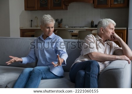 Wound up older wife expresses her displeasure to annoyed husband sit together on sofa at home. Aged wife and husband experiencing marital crisis, lack of understanding between mature spouses, quarrels Royalty-Free Stock Photo #2221060155