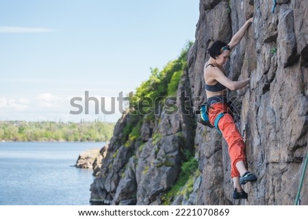 the girl is engaged in rock climbing by the water. a rock climber overcomes a difficult route. sports and fitness in nature.
