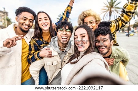 Multiracial group of young people taking selfie portrait picture outdoors - Happy friends having fun together hanging out in city center - Youth concept with guys and girls laughing at camera 