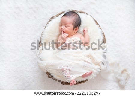 A newborn baby sleeping peacefully in a basket (newborn photo) Royalty-Free Stock Photo #2221103297