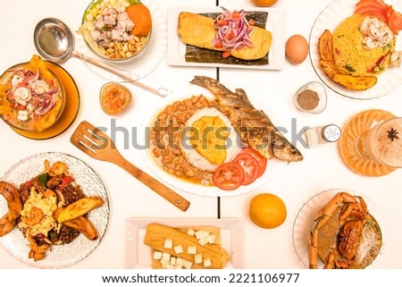 Overhead image of Peruvian and Ecuadorian food dishes with sweet plantains, ceviches, seafood soup, grilled fish, and chaufa rice with beans and chili peppers Royalty-Free Stock Photo #2221106977
