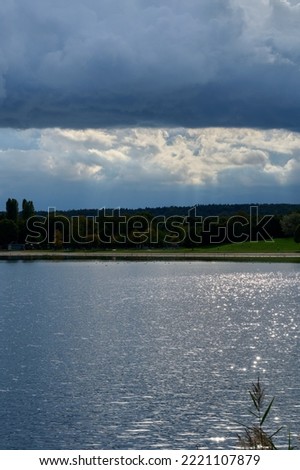 storm clouds over the forest and the lake with the sun behind the clouds