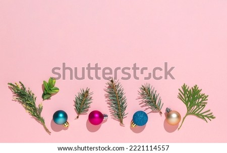 Creative idea with Christmas balls and evergreen branches. Minimal holiday concept and message space on pink background. Flat lay.