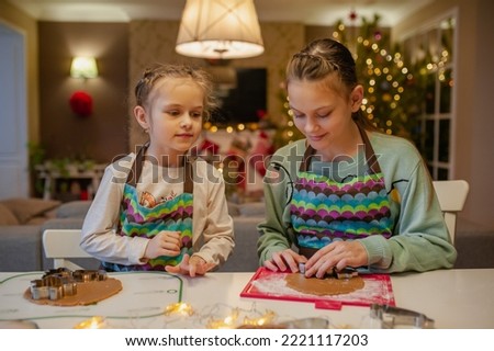 Girls have fun and joyfully prepare Christmas cookies at home in the kitchen