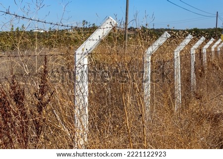  Fencing of white poles with barbed wire in the field.