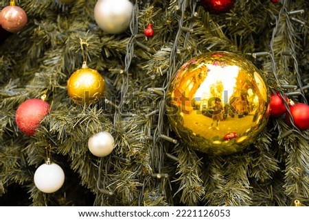Close-up horizontal photo of a decorated Christmas tree with the photographer reflected on a bauble