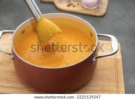 closeup of blender making pumpkin cream soup on dark kitchen counter. Cooking healthy food concept