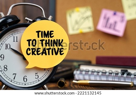Business concept. The alarm clocks have a sticker with the inscription - TIME TO THINK CREATIVE. There are office items in the background in a blurry background.