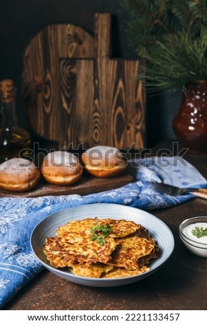 Traditional Jewish festive food for Hanukkah holiday. Jew festival of lights. Potato pancakes Latkes and Sufganiyot jelly doughnuts cooked in oil on wooden table