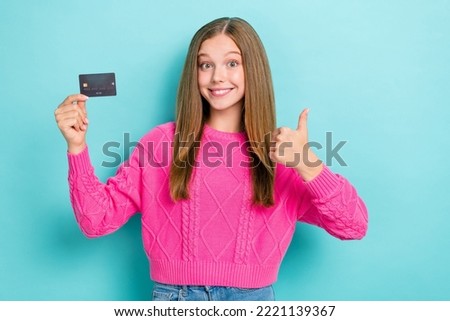 Photo of good mood girl with straight hairstyle wear pink knit sweater approve debit card thumb up isolated on blue color background