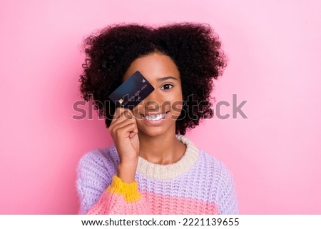 Photo of girlish satisfied optimistic girl with perming coiffure wear knit sweater eye cover debit card isolated on pink color background