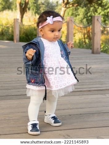 First steps of little girl in summer park. Lifestyle and childhood concept.