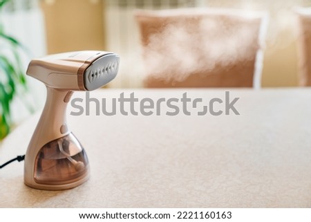 Working portable hand steamer for clothes. steam for ironing clothes. household appliances for the home. Royalty-Free Stock Photo #2221160163
