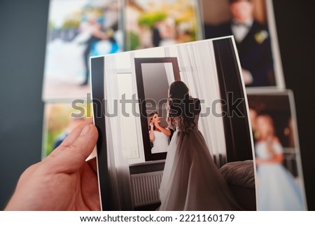 printed wedding photos on a black background and in hand. the concept of preserving the memory of an important event, the services of a professional photographer for the celebration and typography.