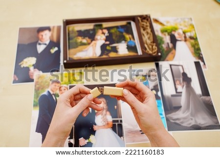printed wedding photos, a wooden box and hands with a flash drive. the concept of preserving the memory of an important event, the services of a professional photographer for the celebration.