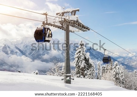 New modern spacious big cabin ski lift gondola against snowcapped forest tree and mountain peaks covered in snow landscape in luxury winter alpine resort. Winter leisure sports, recreation and travel Royalty-Free Stock Photo #2221168405