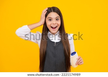 Amazed teen girl. Teenager child girl showing bottle shampoo conditioners or shower gel. Hair cosmetic product. Bottle for advertising mock up copy space. Excited expression, cheerful and glad.